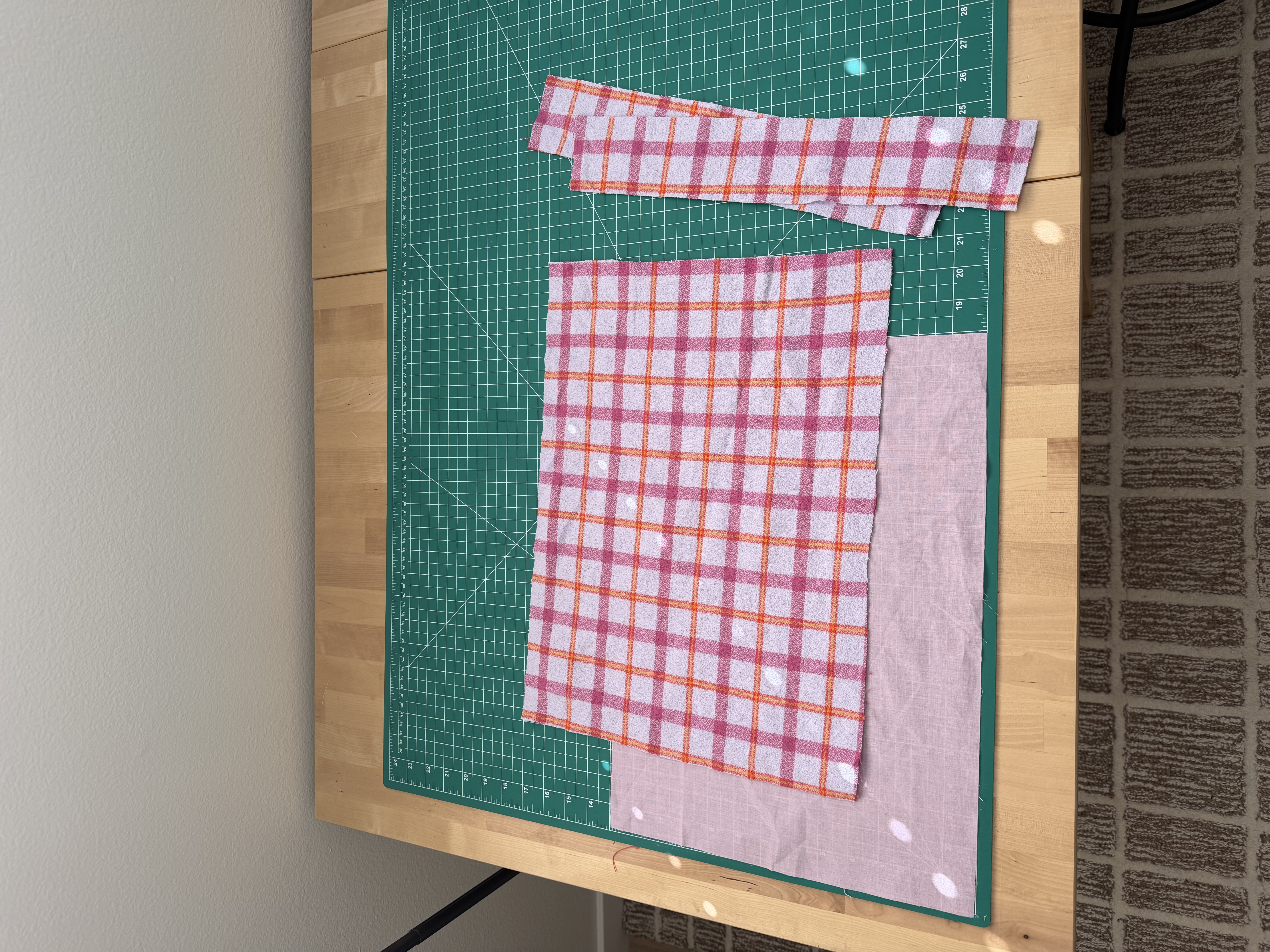 Cut outer fabric and batting pieces for the book sleeve laid out on a cutting mat
